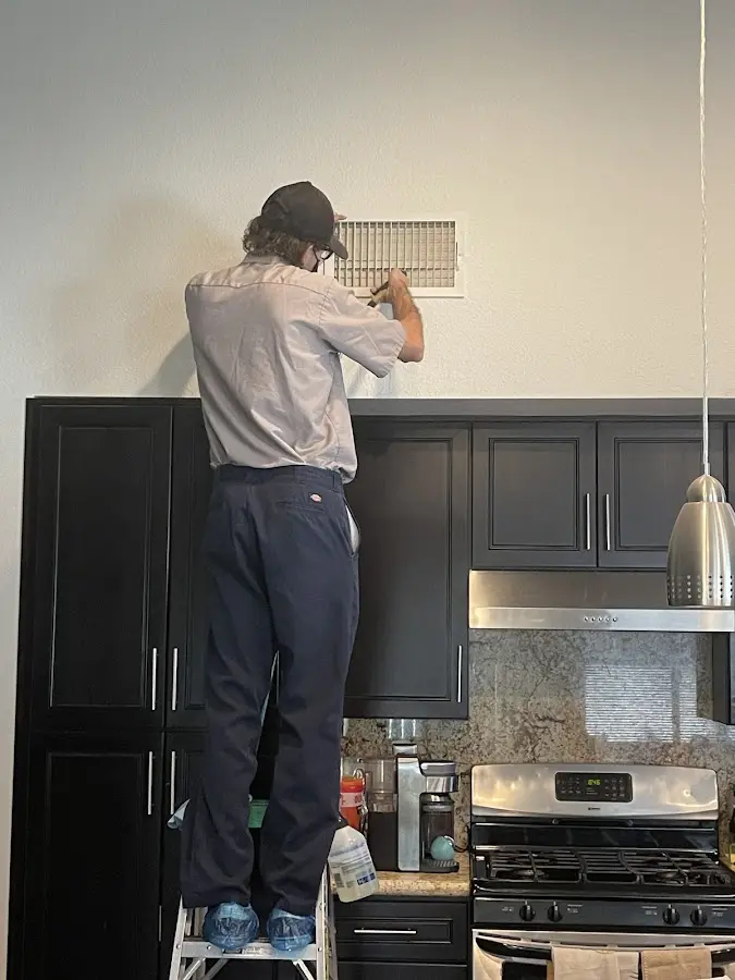 Technician inspecting an air vent during HVAC service in Conley